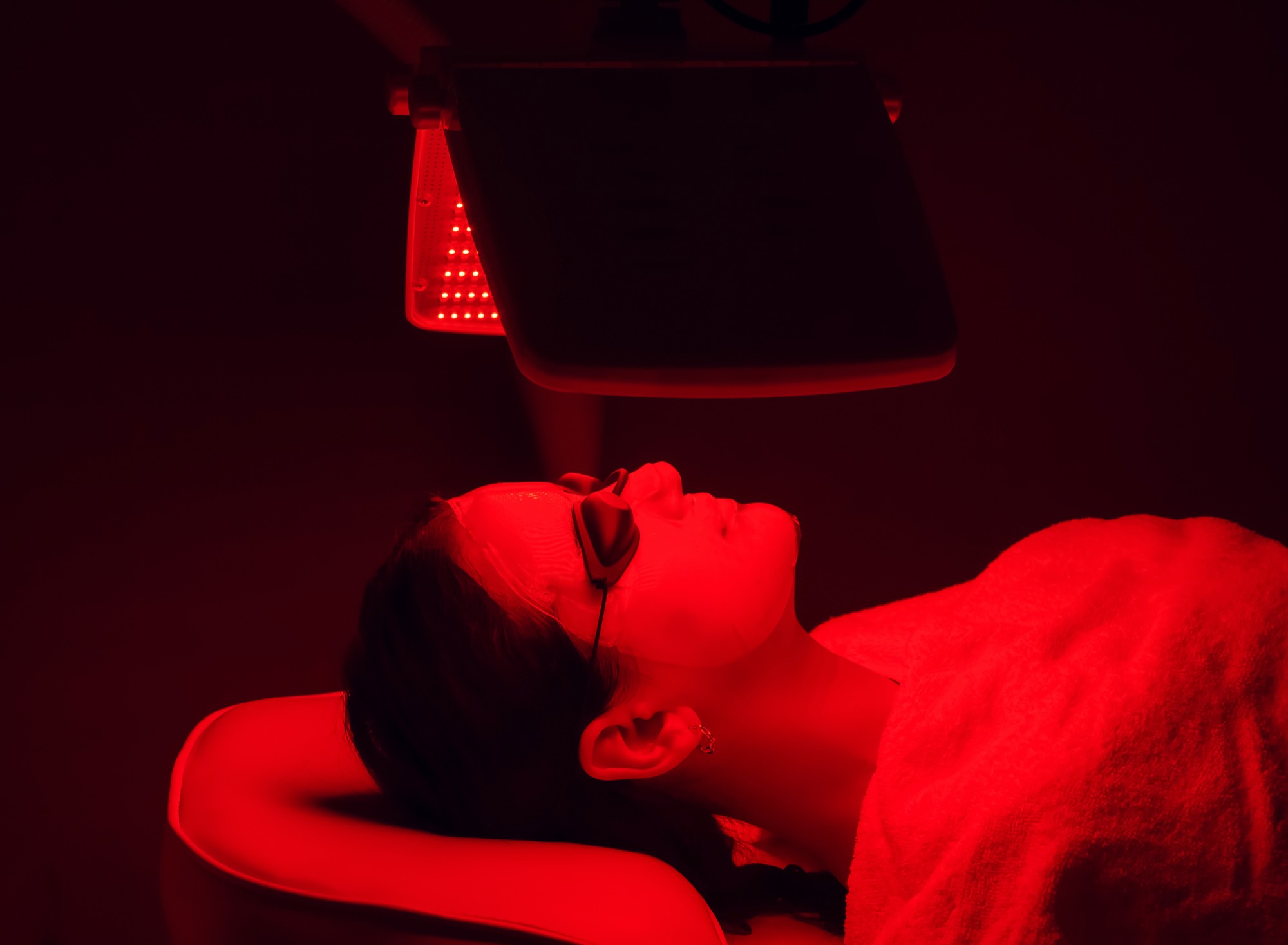 A client relaxing under a red light therapy panel